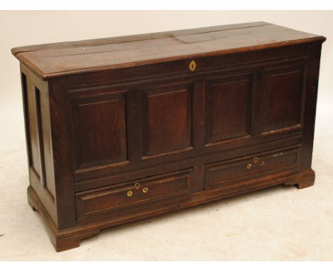 A large oak lidded chest with four panelled front, on stretchered supports with bracket feet, width 155cm.