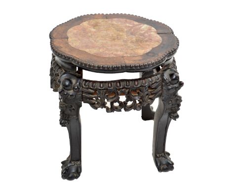 A late 19th/early 20th century Chinese hardwood stand with pink marble inset lobed top above elaborately carved foliate scrol