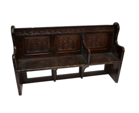 A stained pine pew with carved detail and separating bracket, length 168cm.