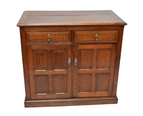 An oak side cabinet with two drawers above two panel cupboard doors to plinth base.
