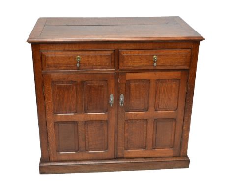 An oak side cabinet with two drawers above two panel cupboard doors to plinth base.