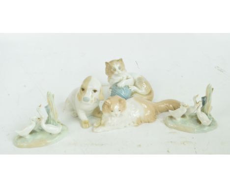 Four Nao animal figures; two cats, one with a ball of wool and two goose groups, also a Porcelanas Miquel Requena puppy (5). 