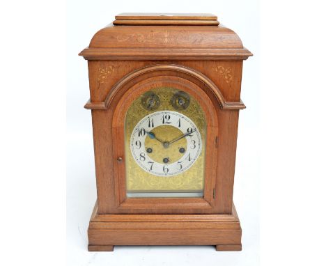 An early 20th oak and inlaid Junghans bracket clock with arched dial, silvered chapter ring with Arabic numerals and chime/si