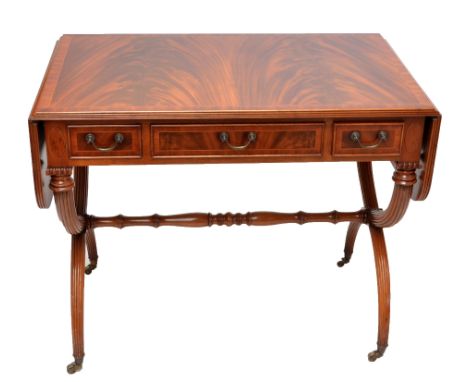 E.G. HUDSON OF SUSSEX; a mahogany and crossbanded Regency style reproduction sofa table with three frieze drawers, fluted swe