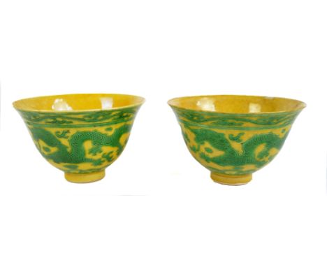 A pair of early 19th century Chinese yellow glazed porcelain bowls painted in green enamels with two five clawed dragons chas
