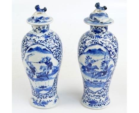 A near pair of 19th century Chinese vases and covers, painted in underglaze blue with two opposing panels depicting battle sc