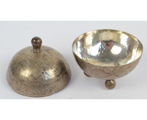 A c.1900 Eastern white metal globular box and cover with ball finial and three feet, overall engraved with ornamental motifs 