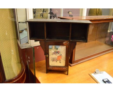 An Arts and Crafts oak wall smoker's cabinet with three sectioned shelf above single cupboard glazed door enclosing a pipe ra