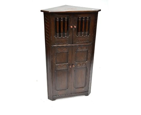 A reproduction oak corner cupboard with twin glazed upper doors and twin panel lower doors by Goodalls of Manchester.