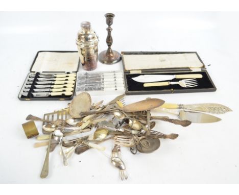 A group of electroplated items including two pairs of fish servers, a candlestick, a cocktail shaker and various loose flatwa