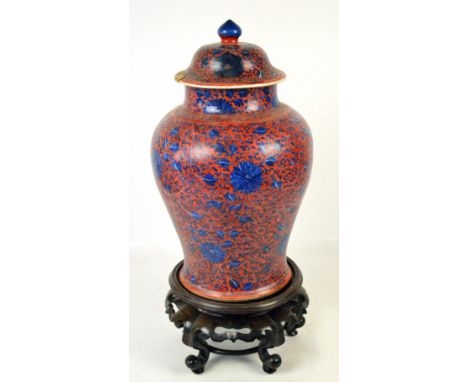 A large Chinese Kangxi clobbered baluster jar and cover painted with blue flowers and leaves on a red ground, blue painted do