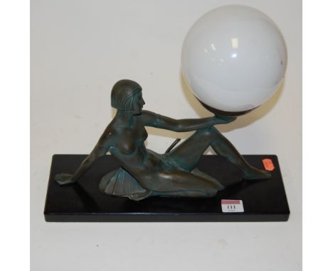 An Art Deco style resin table lamp in the form of a semi-nude dancer supporting a globular glass shade 