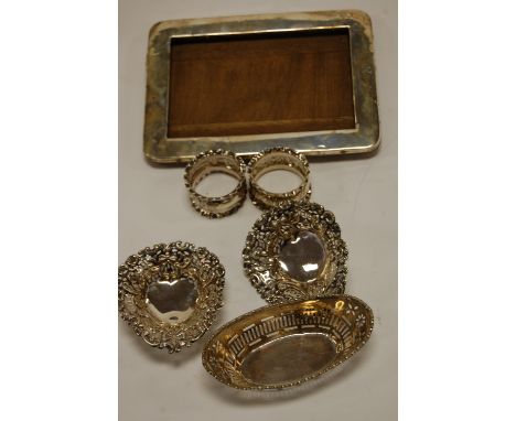 A pair of late Victorian pierced silver bonbon dishes; together with a silver rectangular easel photograph frame; and napkin 