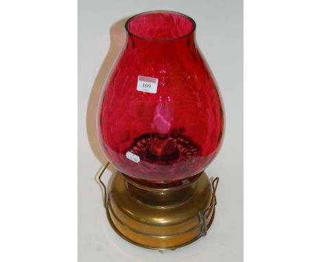 An early 20th century brass oil lamp having cranberry glass shade later converted to electricity, height 43cm