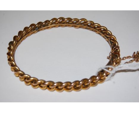 A 9ct gold curb link hinge bangle with safety chain, 15.1g