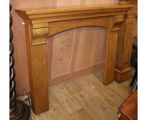 A reproduction oak fire surround, W.137cm H.110cm
