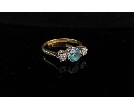 An 18ct gold three stone ring, central pale blue stone flanked by 0.10ct approx diamonds. Size K/L, 2.3g 