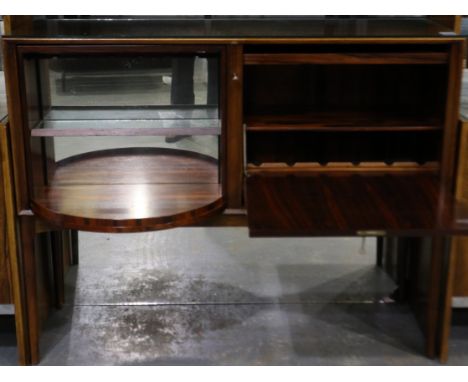 A mid 20th century rosewood drinks cabinet having a rotating bottle cupboard with mirrored back and a drop front cupboard, 12