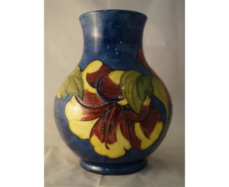 A Moorcroft pottery vase of baluster form decorated in a hibiscus pattern on a blue ground, impressed factory marks and origi