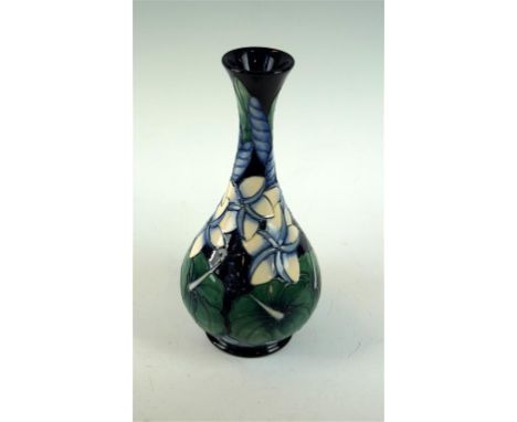 A modern Moorcroft pottery trial vase of baluster form, decorated with white lilies on a cobalt blue ground surrounded by gre