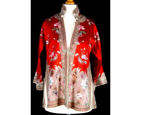 A Chinese embroidered jacket, early to mid 20th century, of vibrant red colour, the lower third with wave and lotus design an