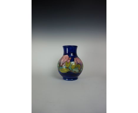 A Moorcroft Pottery vase of baluster form, decorated in a Magnolia pattern on a blue ground, green signature and impressed fa