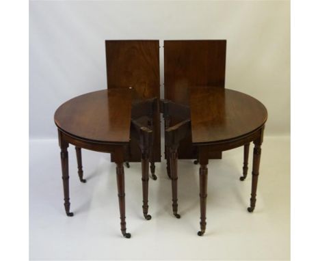 A George IV mahogany D-end dining table with two extra leaves supported on a pair of double gate legs, the twelve ring turned