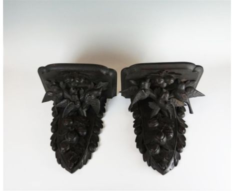 A pair of Black Forest style oak wall brackets, early 20th Century, the upper tier of each with lobed edges, above a tapered 
