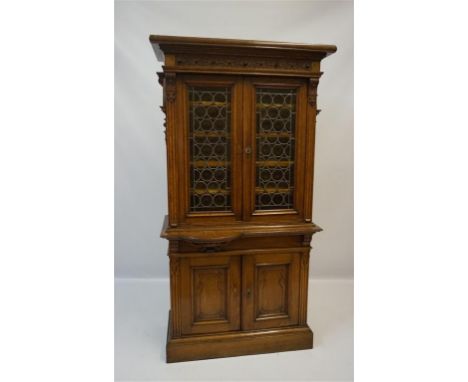 A late 19th century continental oak tall cabinet, featuring a moulded cornice and blind fret frieze above two stained glass a