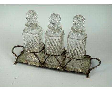 A Hukin & Heath silver-plated rectangular decanter holder, having planished decoration inside a wavy rim holding three cut gl