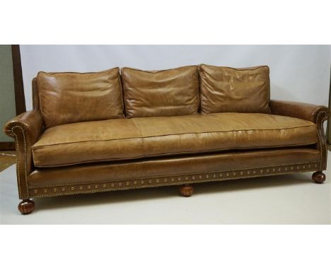 A super quality Ralph Lauren period style brown leather sofa, applied with brass studs and raised on front fluted ball feet, 