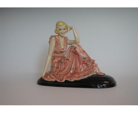 A Goldscheider Art Deco figurine of a girl seated wearing a red floral dress raised on an oval black plinth base, impressed f