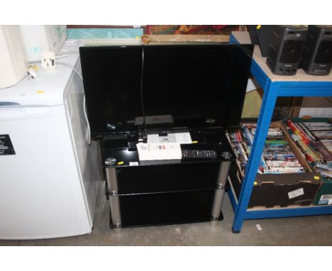A glass three tier TV stand together with a Panasonic flat screen television and remote controls