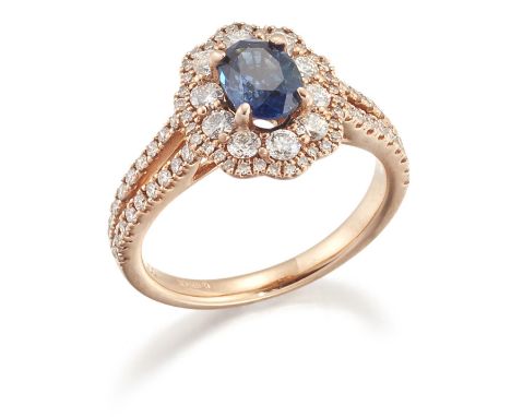 AN 18 CARAT GOLD SAPPHIRE AND DIAMOND CLUSTER RING, an oval-cut sapphire within a shaped border of round brilliant-cut diamon