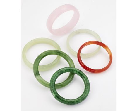 A GROUP OF FIVE JADE AND OTHER HARDSTONE BANGLES AND A GREEN GLASS BANGLE. (6) Measure 6.5cm in diameter and smaller