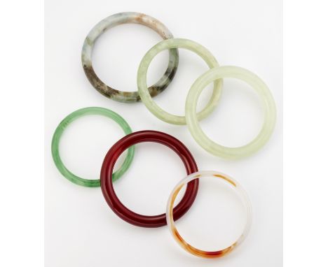A GROUP OF FIVE JADE AND OTHER HARDSTONE BANGLES AND A GREEN GLASS BANGLE. (6) Measure 7cm in diameter and smallerCONDITION R