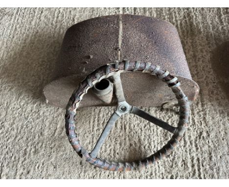 A vintage car steering wheel and fuel tank.