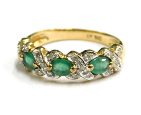 A modern emerald and diamond set 9ct gold dress ring, the design of three opal emeralds cross set with five diamonds in four 