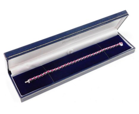 A ruby and diamond line bracelet, set with thirty oval cut rubies, each 3.8mm x 3mm x 1.2mm, totalling 5.52cts overall, in fo