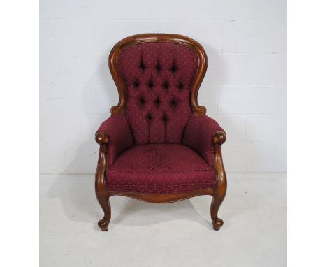 A Victorian style mahogany framed button-back armchair, with carved detailing, raised on French cabriole legs