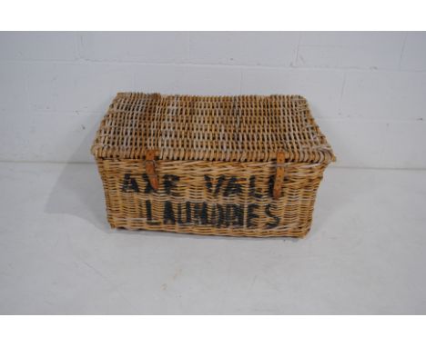 A vintage wicker laundry basket, named to 'Axe Vale Laundries, Axminster' - length 77cm, depth 57cm, height 37cm