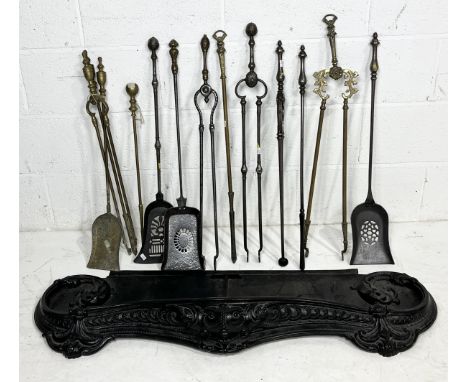 A collection of fireside tools along with a cast metal fender with scrolled decoration