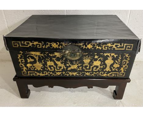 An antique Chinese leather trunk with gilded decoration on lacquered stand, height 40cm, 60 cm width and 40cm depth