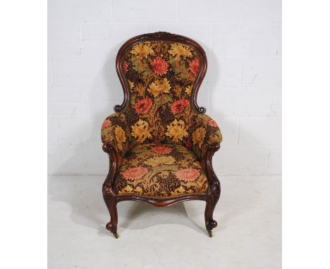 A Victorian mahogany framed button-back armchair, with carved detailing raised on French cabriole legs