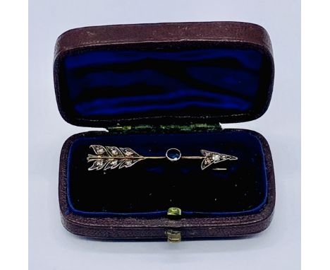 An unmarked rose gold (tested 9ct) brooch in the form of an arrow set with diamonds and a sapphire