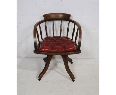 A 20th century oak swivel office chair, with turned spindle back and red leather seat with button-back detailing