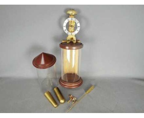 A modern Hermle, skeleton type wall clock in twin section, cylindrical glass case, silvered chapter ring with Roman numerals,