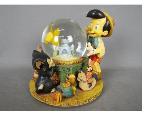 A Disney musical snow globe entitled 'Toyland' featuring Pinocchio, approximately 20.5 cm (h).