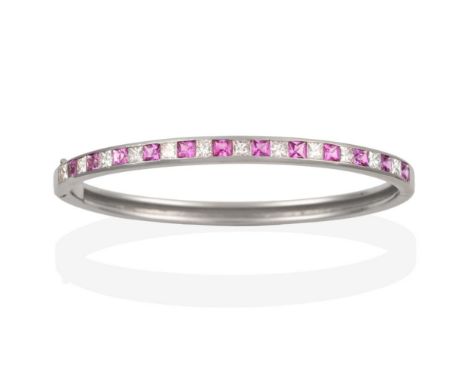 A Pink Sapphire and Diamond Bangle, princess cut diamonds alternate with square cut pink sapphires, in white channel settings