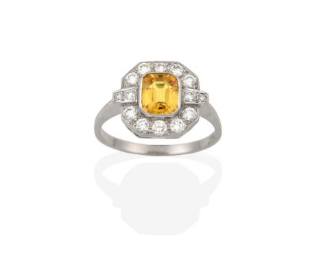 An Art Deco Style Yellow Sapphire and Diamond Ring, the central emerald-cut yellow sapphire within a border of round brillian